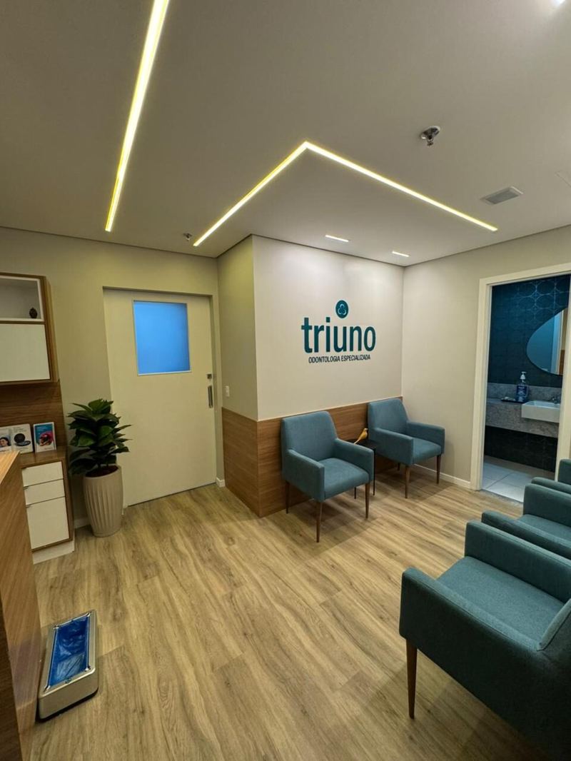 Triuno: espera com iluminação em sanca e logo da clínica